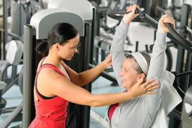 Older woman training in a gym with a trainer